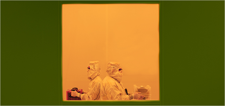 Photo of two technicians moving through the C2MI yellow room