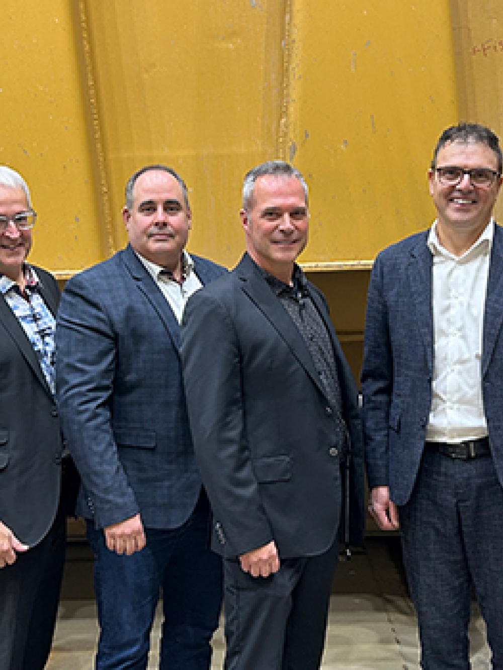 Groupe de personnes debout dans un atelier industriel, posant près d’une bannière d’ASDR et d’un drapeau du Québec.