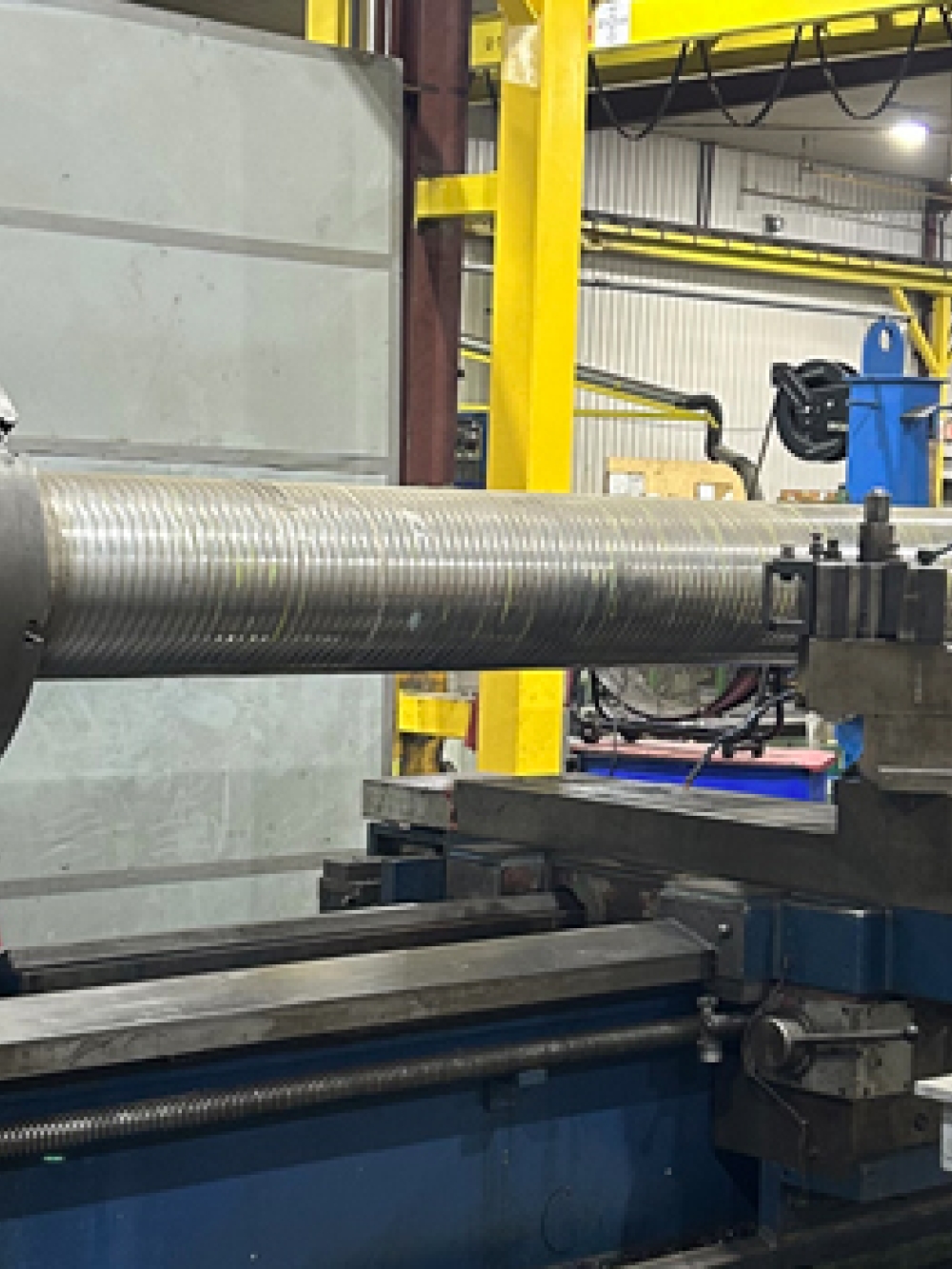 Grande machine industrielle MT 700 en atelier, équipée d’un long cylindre métallique fixé pour l’usinage, avec des structures et équipements d’usine en arrière‑plan.