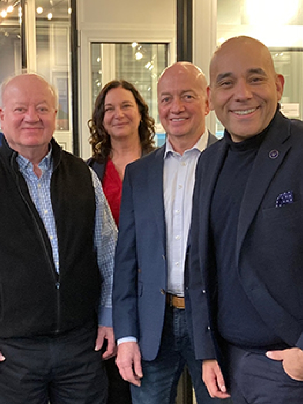 Groupe de sept personnes posant à l’intérieur d’un espace industriel ou commercial, devant des fenêtres et des présentoirs.