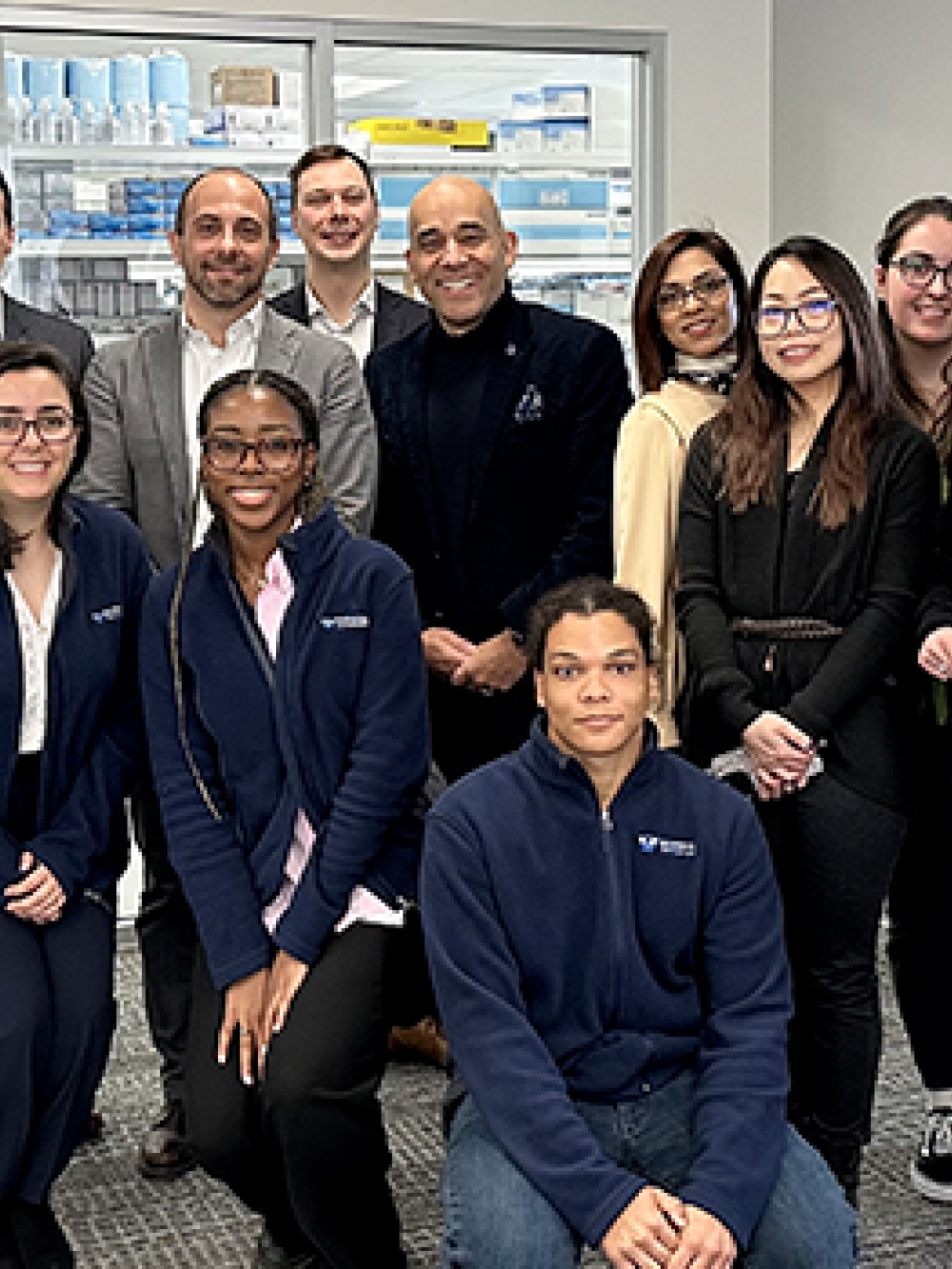 Groupe de personnes réunies dans un laboratoire laissant voir du matériel scientifique en arrière‑plan.